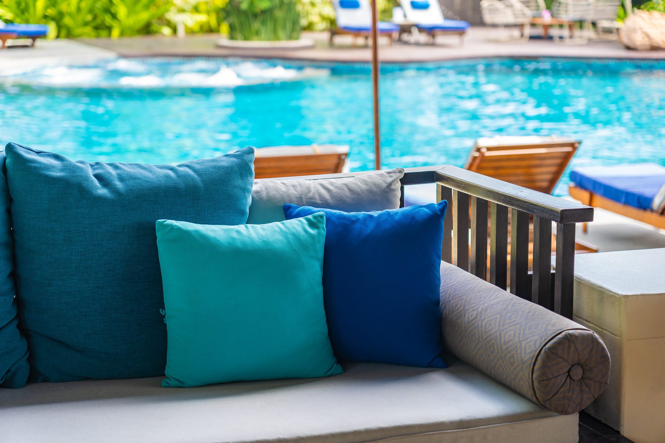 Throw pillows in different shades of blue on gray outdoor furniture