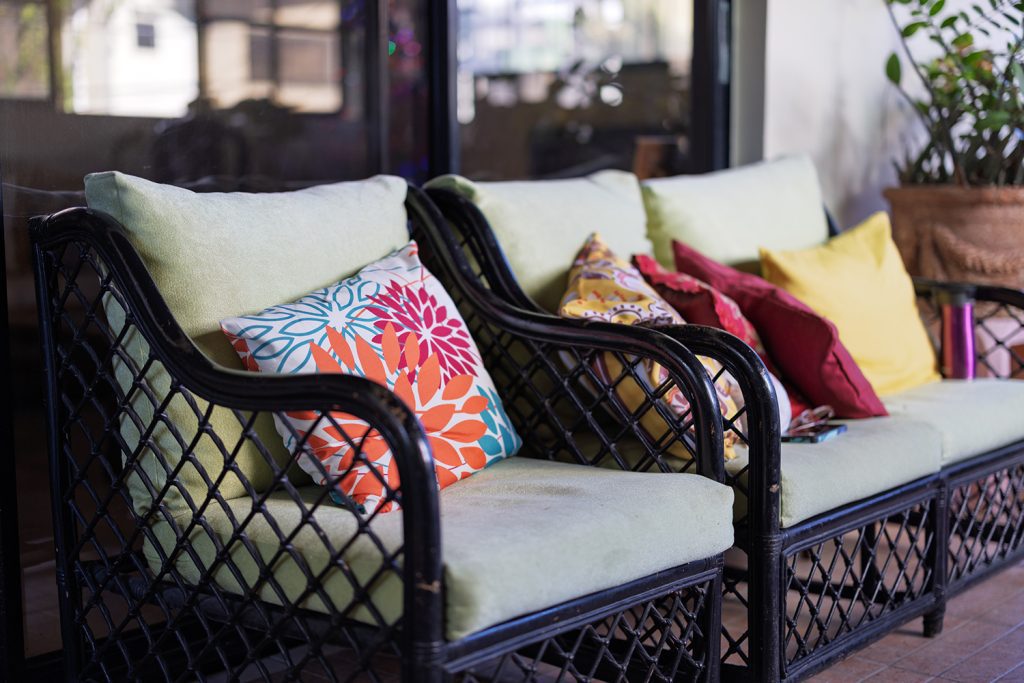 three outdoor chairs with green cushions and colorful throw pillows