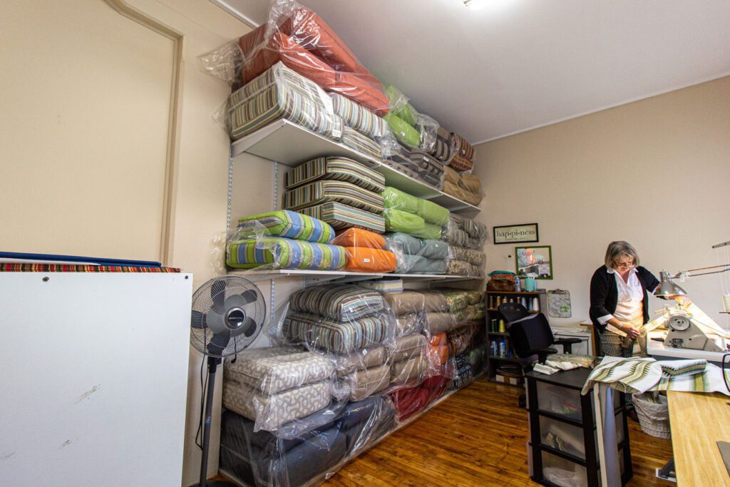 A person working on a fabric project, with many packages of fabric on shelves beside them